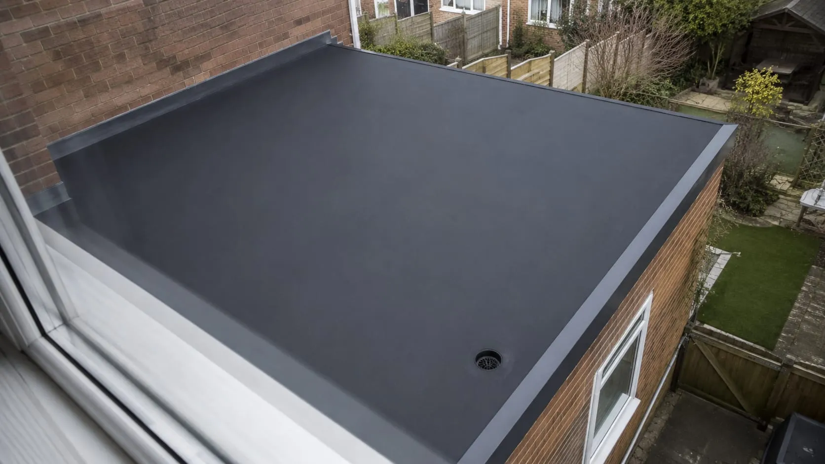 A completed EPDM rubber flat roof on a single-storey rear extension, laid seamless with a grey edge trim.