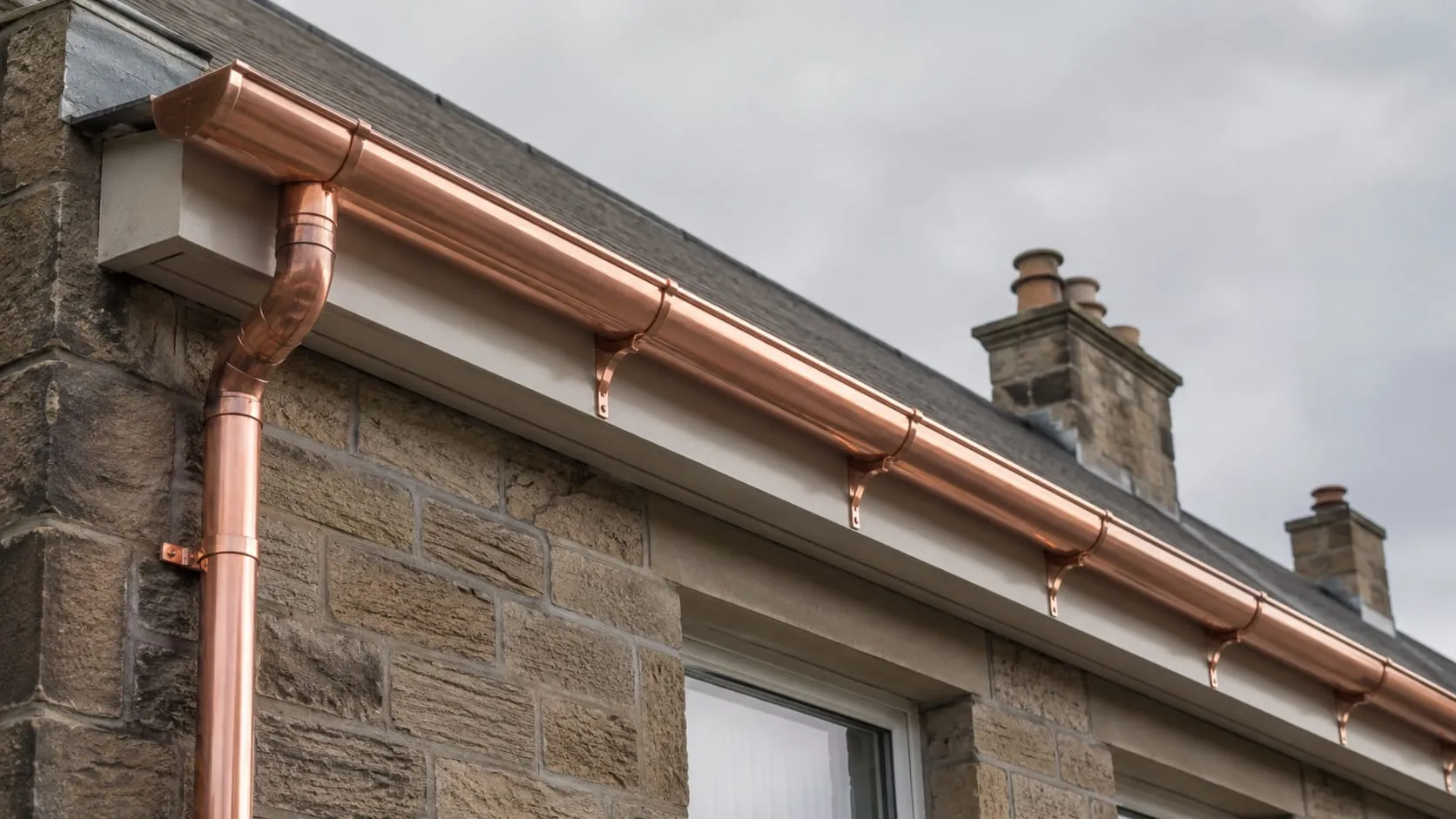 New half-round copper guttering and downpipe running level along a newly painted fascia.
